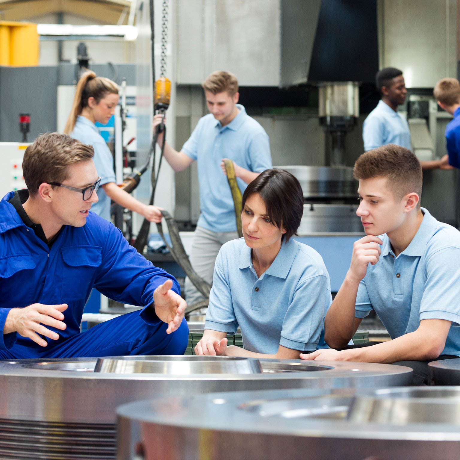Three factory workers in workspace talking.
