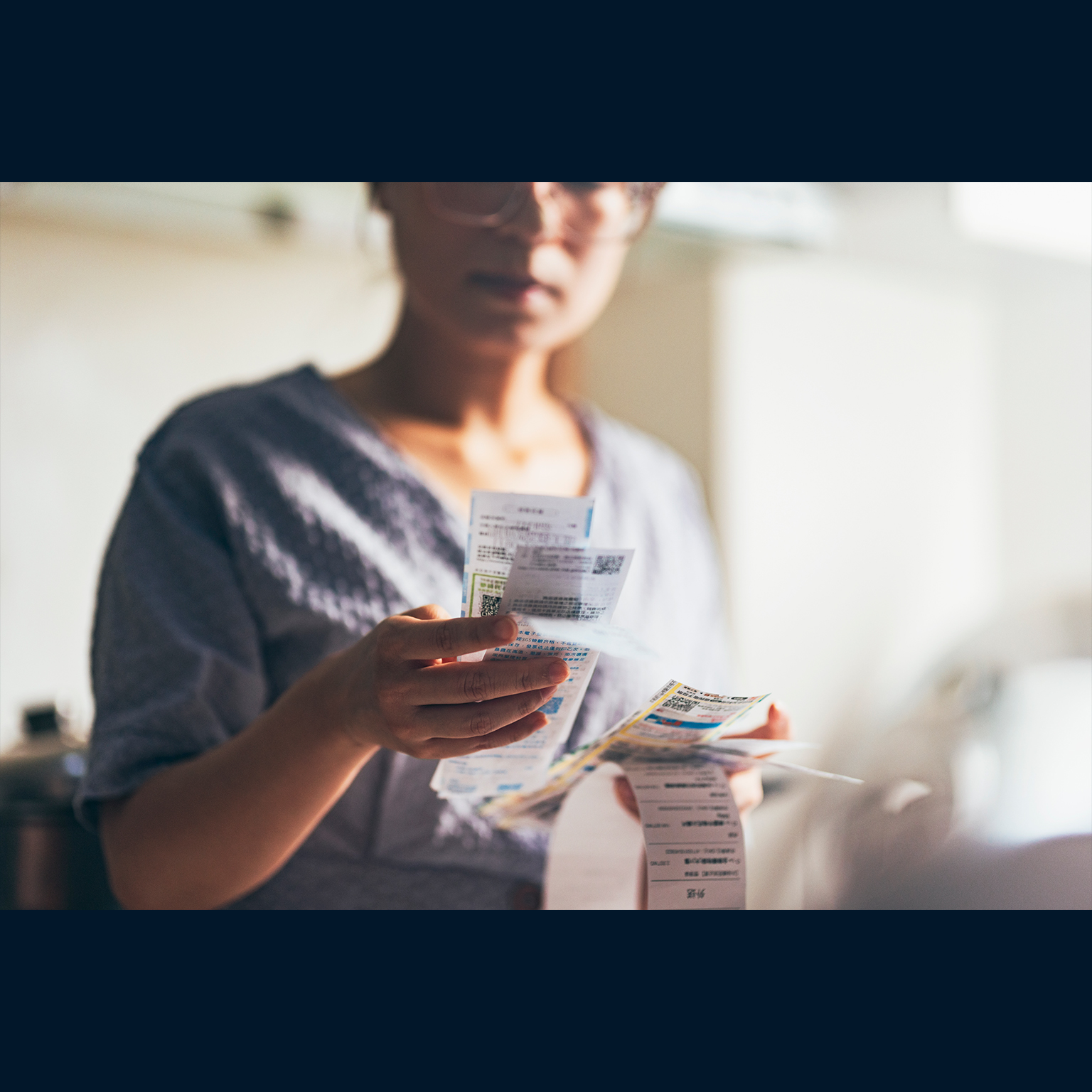 Asian women examining the shopping receipt at home - stock photo