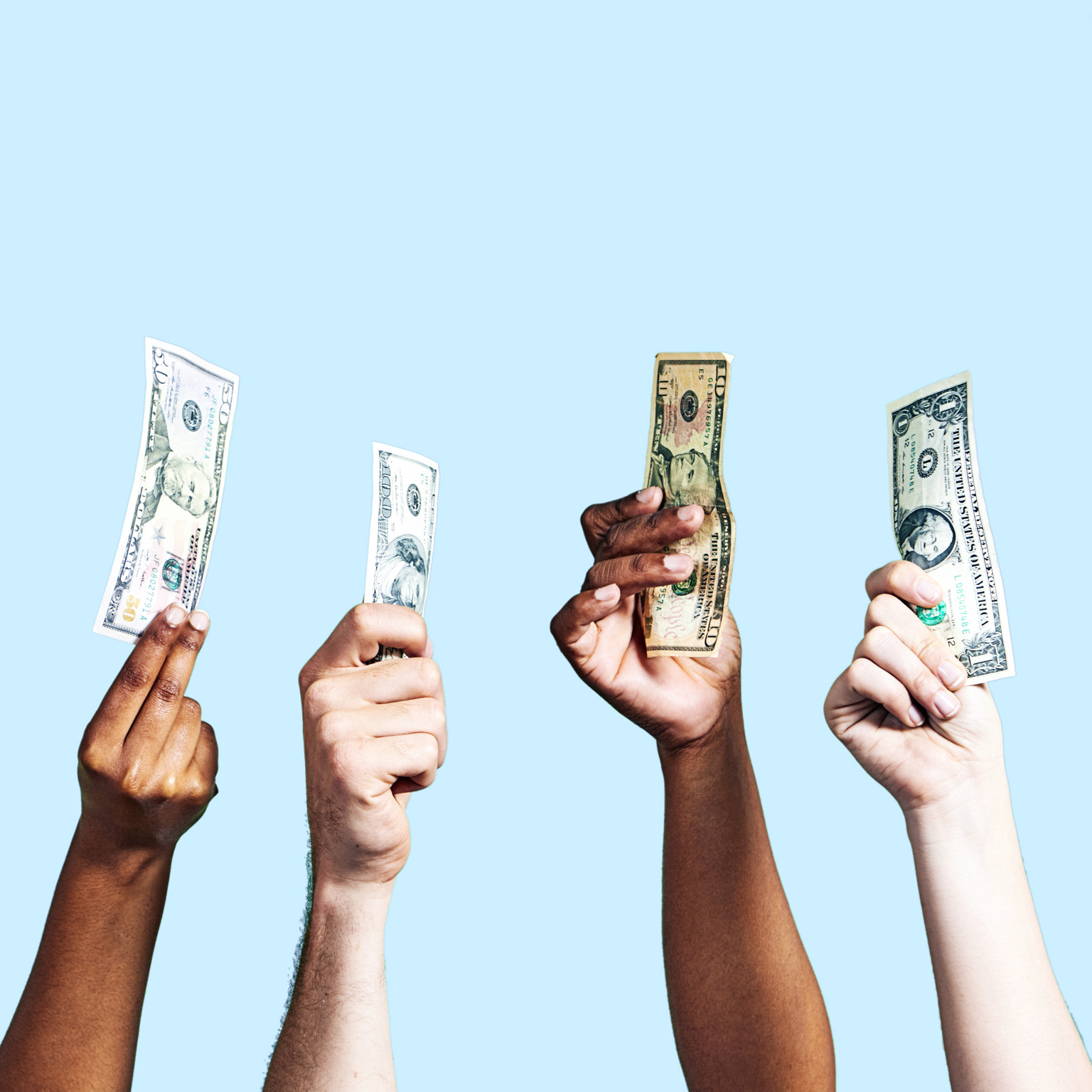 A diverse group of hands holding up US dollar banknotes of various denominations on light blue background.