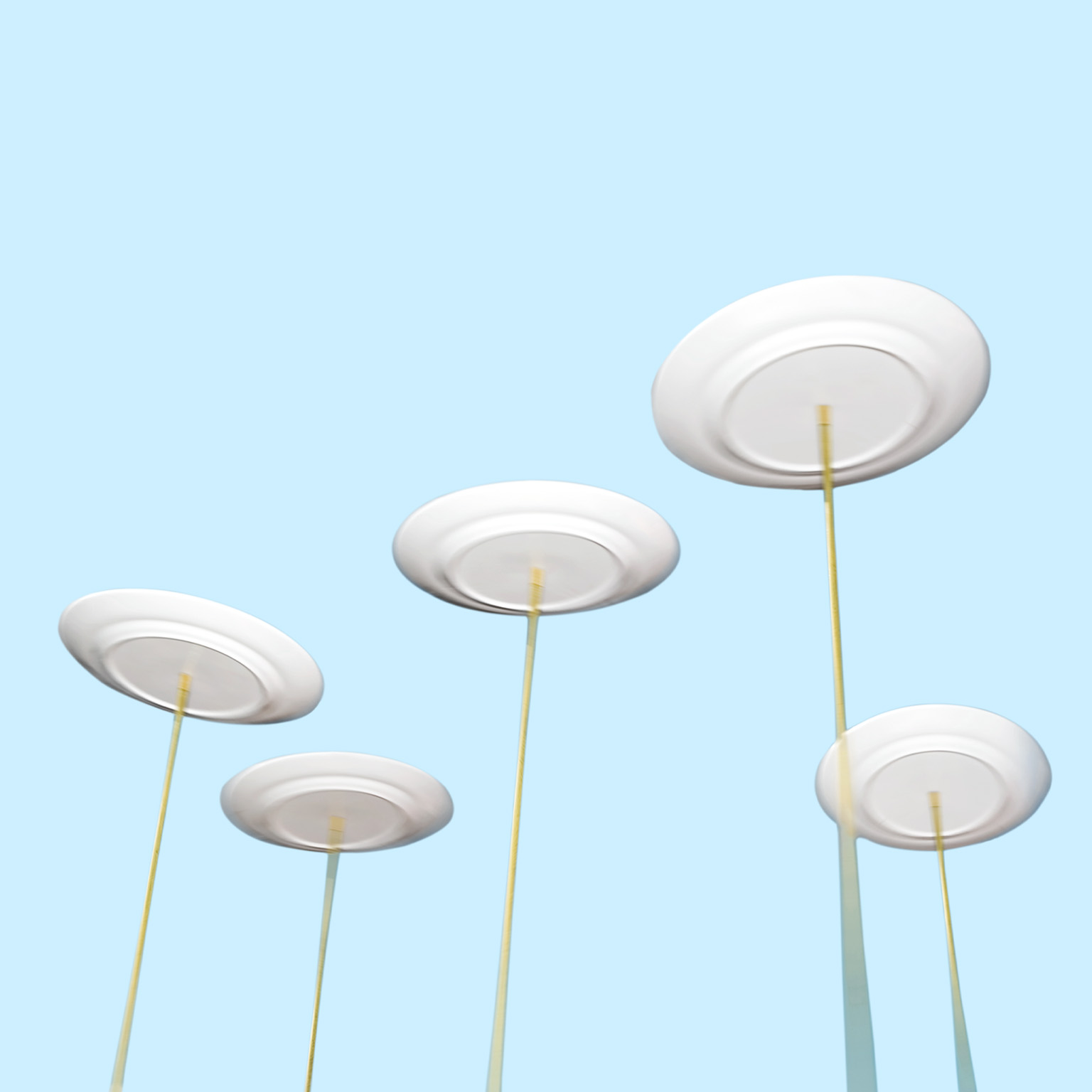 Spinning plates balancing on long poles against a light blue background.