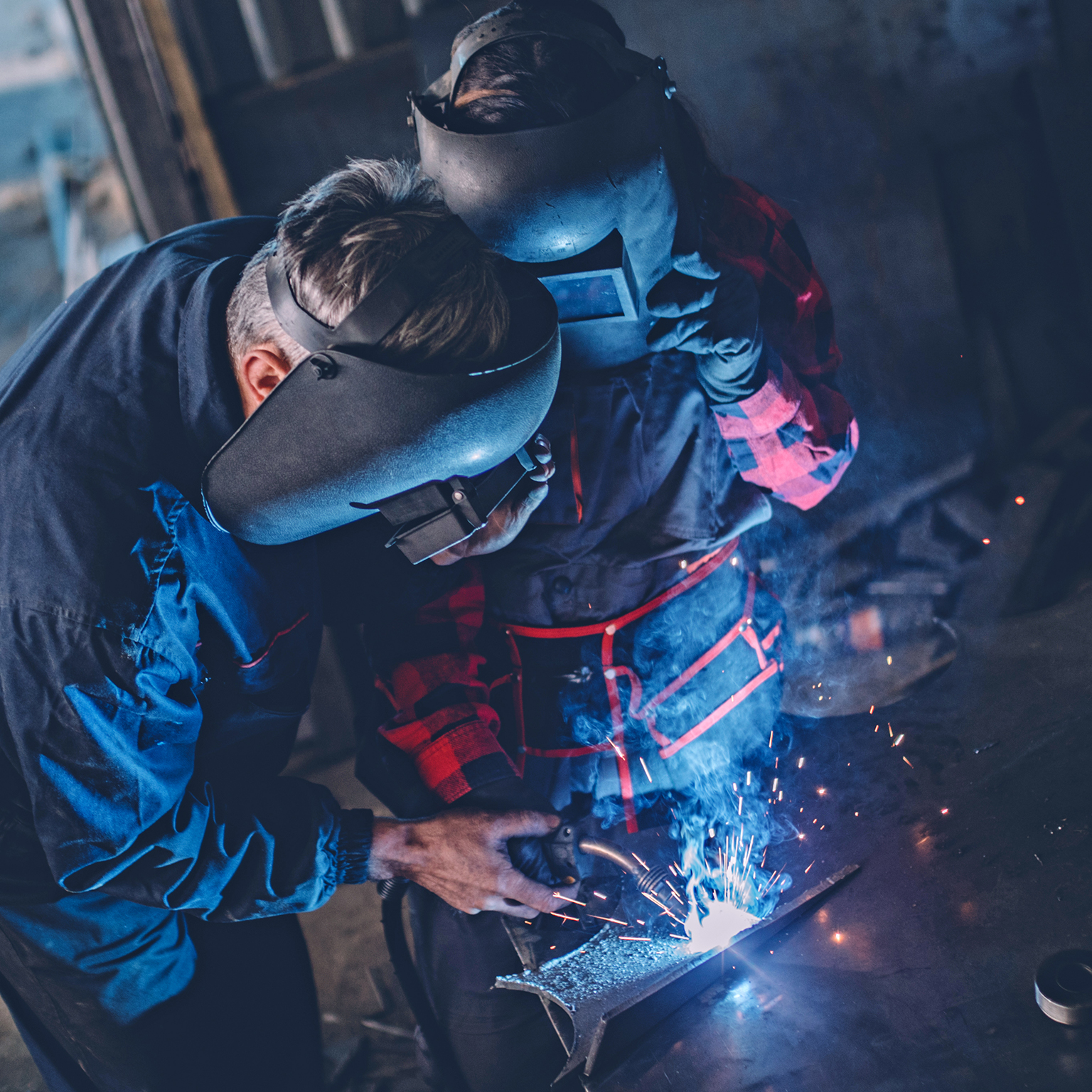 Man and woman welding together in workshop