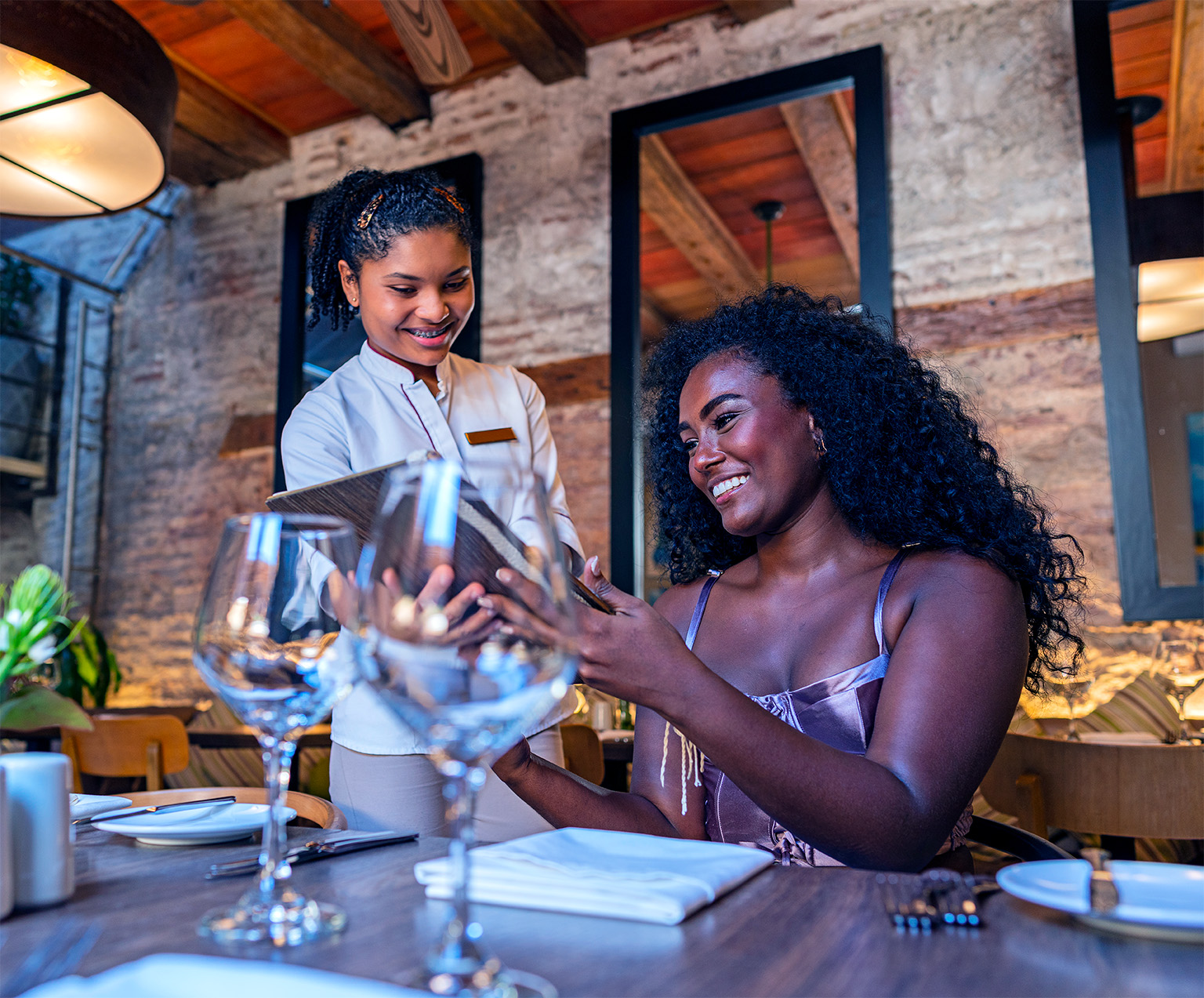 Image of a smiling woman ordering in a fancy restaurant.