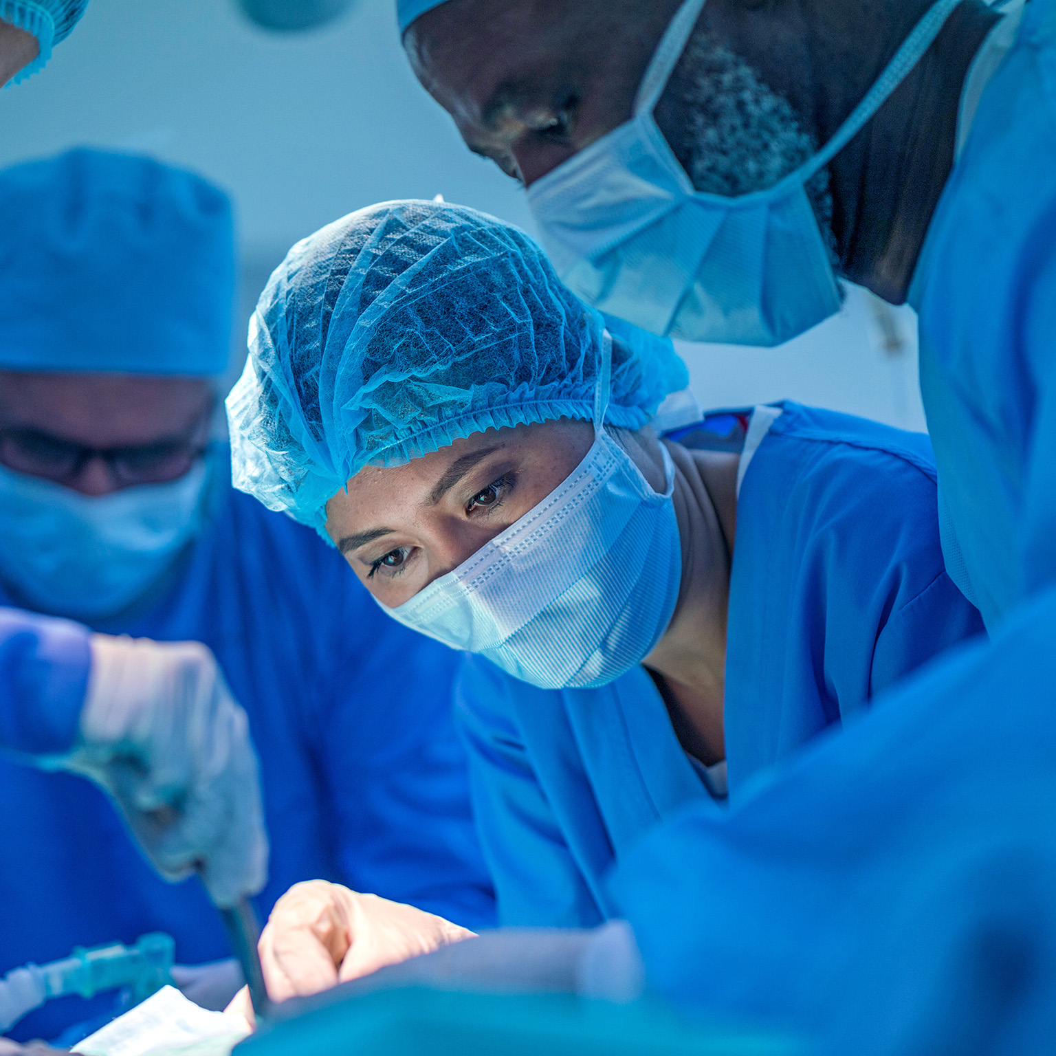 Healthcare workers performing surgery on patient in operating room.