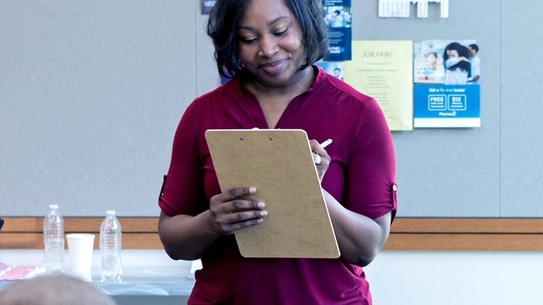 Confident mid adult woman takes attendance during a community group event. - stock photo