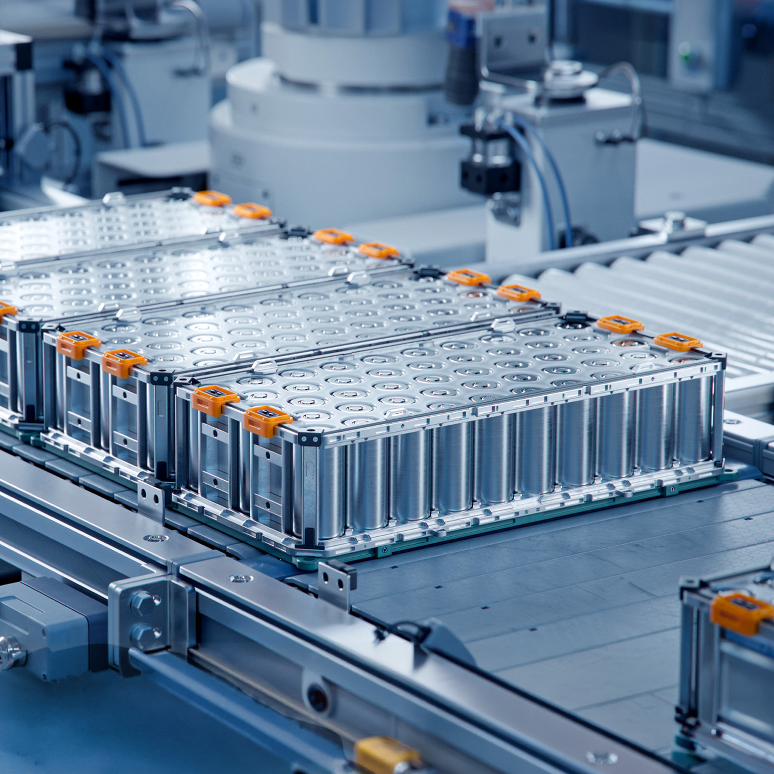 Several large lithium-ion battery modules arranged on an automated production line inside a clean, high-tech manufacturing facility.