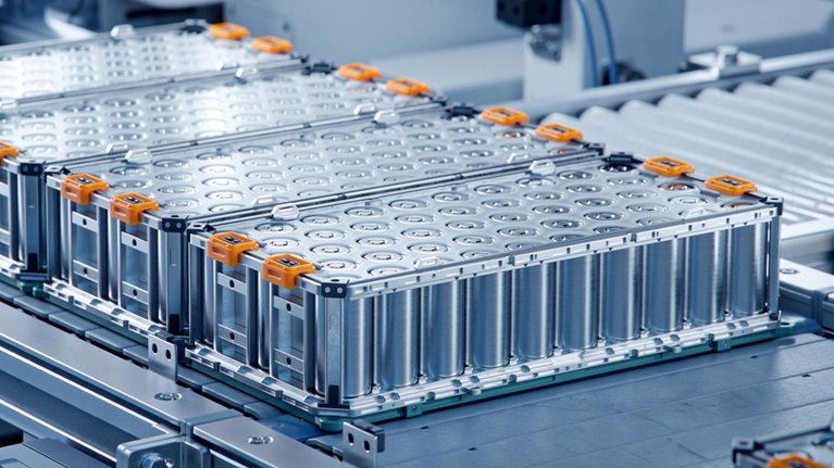 Several large lithium-ion battery modules arranged on an automated production line inside a clean, high-tech manufacturing facility.