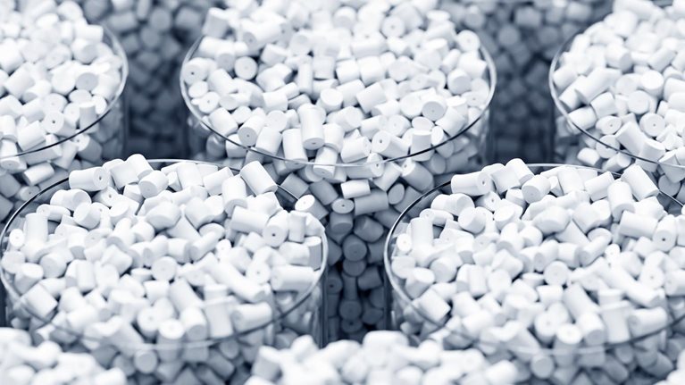 Multiple transparent containers filled with small white cylindrical plastic pellets arranged in a repeating pattern.